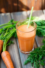 Carrot fresh juice in a glass and carrots with tops of vegetable