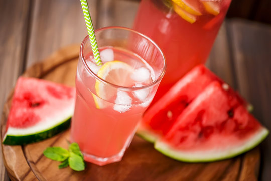 Watermelon lemonade with lemon and mint in a glass and a jug on