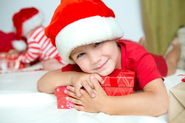 little cute kid in santas red hat with handmade gifts