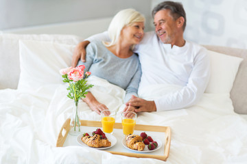 Obraz na płótnie Canvas Senior couple enjoying breakfast in bed 
