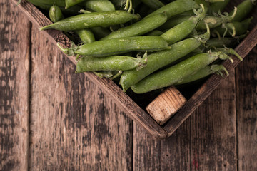 pods of green peas on a wooden table, rustic style,healthy food
