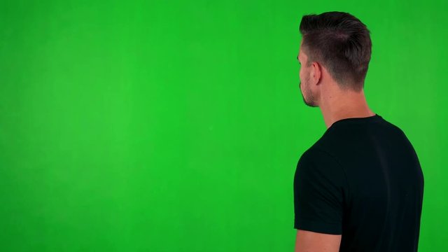 young handsome caucasian man looks around - shot on back - green screen