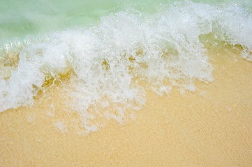 Foamy wave is incident on the yellow sand. The beach in a tropical Paradise, recreation, relaxation. Sea background