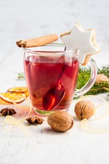 Homemade butter nuts star shaped cookie with icing, pine, orange slices,cinnamon, anise, walnuts and golden ribbon over white wood background. A cup of berry tea. Christmas decoration.