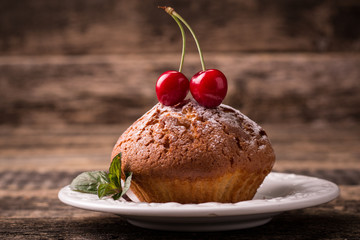Tasty muffin with cherry and mint on vintage wooden background