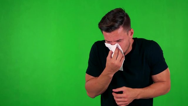 young handsome caucasian man blow one's nose - green screen - studio