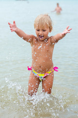 Fototapeta na wymiar Adorable toddler girl playing with beach toys on white sand beach