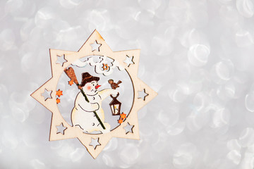 christmas decoration snowman in a star on  silver background, wooden xmas decor  for christmas tree.  postcard concept with copy space and  with place for text