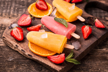 refreshing fruit popsicle lollies on wooden table with berries and fruits