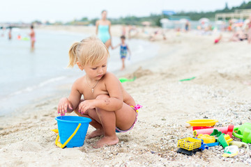 Adorable toddler girl playing with beach toys on white sand beach