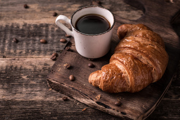 Breakfast with coffee and croissants on wooden vintage table