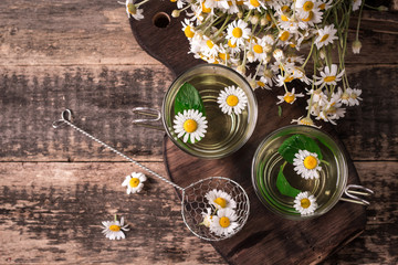herbal chamomile tea on a wooden table. Chamomile tea in a transparent cup and camomile flowers on wooden table. Herbal tea for baby's stomach. Copy space.