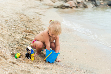 Adorable toddler girl playing with beach toys on white sand beach