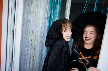 Two children, brother and sister, are dressed in suits for Halloween.
