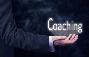 Businessman holding a Coaching Concept