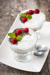 Chia yogurt with raspberries in a glass cup on wooden table


