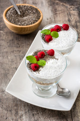 Chia yogurt with raspberries in a glass cup on wooden table


