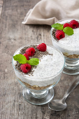 Chia yogurt with raspberries in a glass cup on wooden table

