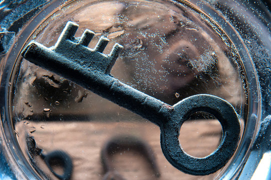 Old rusty key on the bottom of glass of water