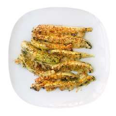 Zucchini baked with cheese and herbs on white plate. Appetizing courgette in the form of sticks.  Vegetarian kitchen. Vegetable course.