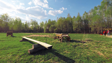 Smooth steady camera slide shot around Russian wooden cart in a field, clean blue sky with sun...