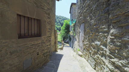 RUPIT CATALONIA SPAIN - JULY 2016: Smooth camera steady wide angle shot along narrow street in the old european spain village goes down, high colorful ancient walls with windows, clear sky with sun