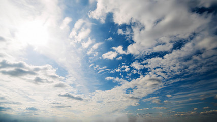 Beautiful summer day sky. Clear crisp cloudscape with large, building clouds, light rays and sun flare, perfect for digital composition background. Wide angle panorama lens
