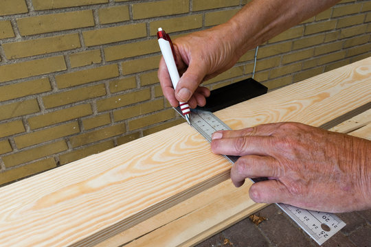 carpenter holding a set-squere and draws a line