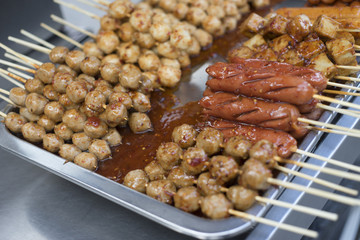 close up many type of  grilled meat ball and sausage with sauce put on metal plate,thai street food