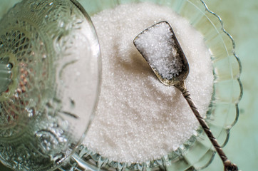 Opened glass jar with sugar. Standing on wooden table