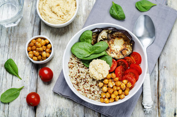 Mediterranean quinoa hummus bowl with eggplants, tomatoes and sp