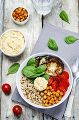 Mediterranean quinoa hummus bowl with eggplants, tomatoes and sp