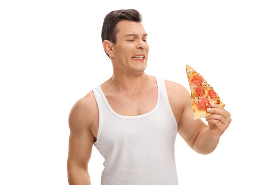 Disgusted Young Guy Looking At A Slice Of Pizza