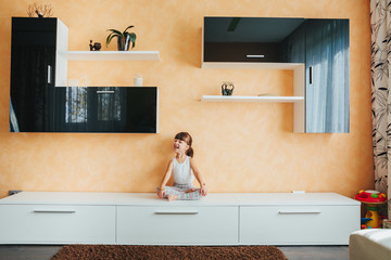 girl sitting in the lotus position on the furniture. Yoga