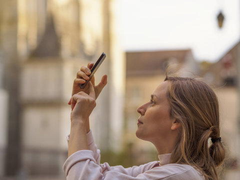 France, Chartres, young woman taking picture with smartphone in front of Notre-Dame de Chartres