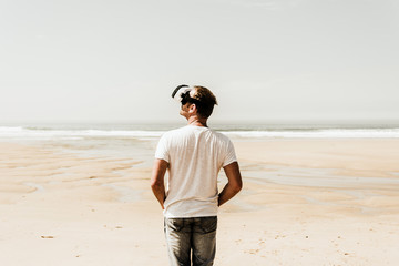 Mature man standing on the beach wearing VR glasses