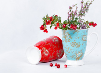 ripe lingonberries and varicolored cups with ornament