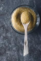 Brown sugar in the glass bowl on the stone background vertical