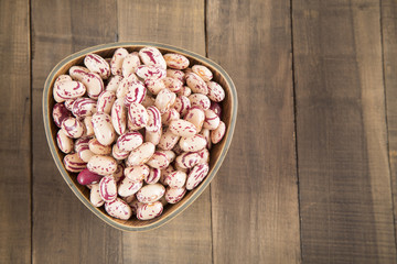 Raw pinto beans in bowl on wooden table