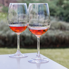 Two glasses of rose wine on a white table in a garden