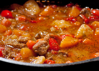 Meat and vegetable stew cooking in a black cast iron pot