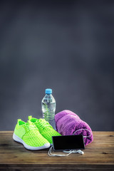 Pair of yellow green sport shoes towel water smart pone and headphones on wooden board. In the background forest or park trail.Accessories for running sport. - obrazy, fototapety, plakaty