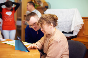 two friends with disability in rehabilitation center, watching digital tablet - 122167013
