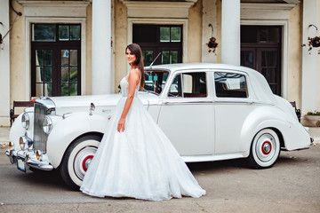 Bride standing by the classic car and smiling