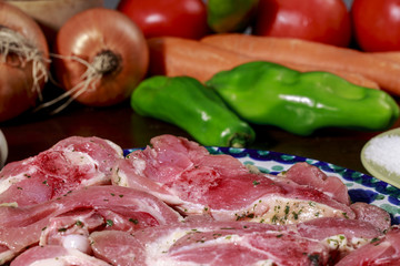 Dish with turkey cutlets marinated with garlic and parsley in front of salt dish and different vegetables