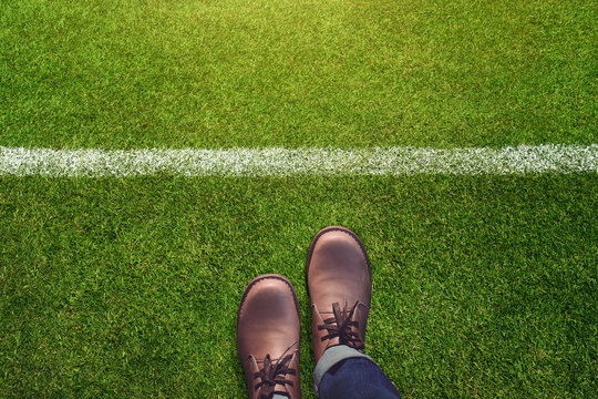 Male with Leather Shoes and Jeans Standing and Steps behind a line on Green Grass Field , Top view