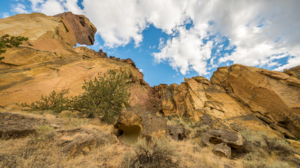 Fototapeta na wymiar Unusual shaped rocks on the background of cloudy sky. Beautiful landscape of yellow sharp cliffs. Smith Rock state park, Oregon