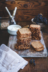 Tower of sliced rye bread with plate of cream cheese and grape fruit behind.