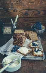 Tower of sliced rye bread with plate of cream cheese and grape fruit behind.