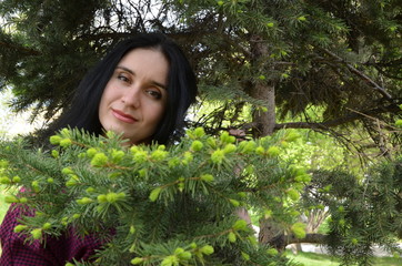 Naklejka premium brunette girl with long hair on a background of green pine branches in the forest, long beautiful hair, natural beauty